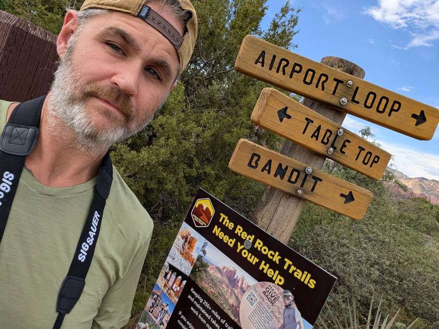 Frank beside a trail sign reading BANDIT