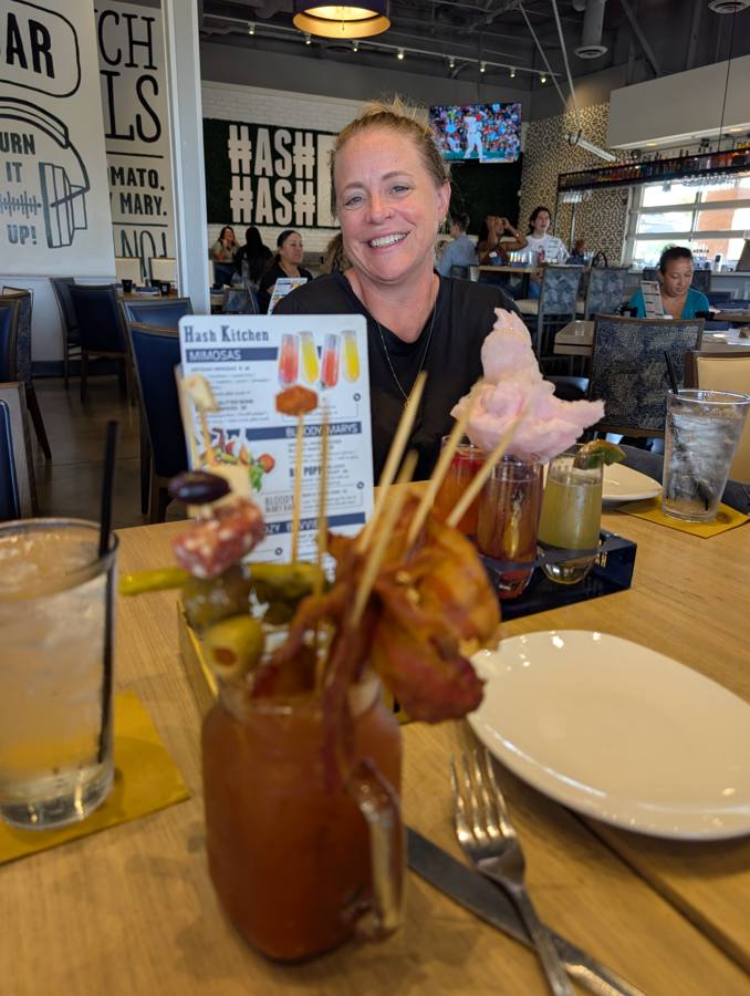 Jessica smiling behind an over-built bloody mary at Hash Kitchen