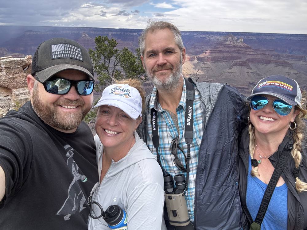 Foursome selfie at the canyon rim under storm clouds